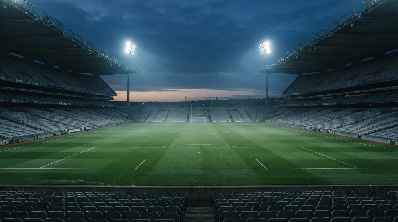 Een leeg voetbalstadion met lichtmasten bij schemering