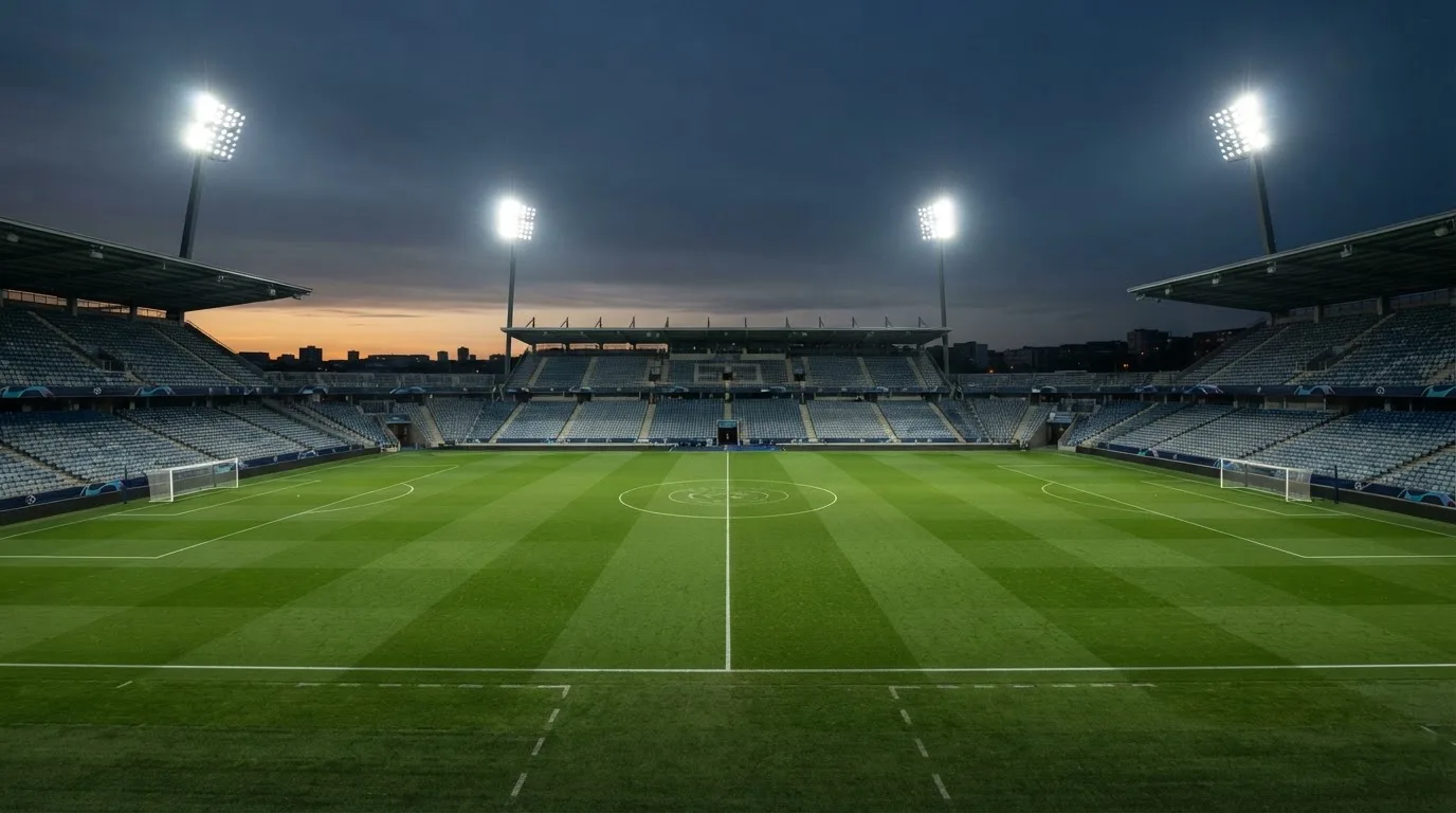 Een leeg voetbalstadion met lichtmasten bij schemering