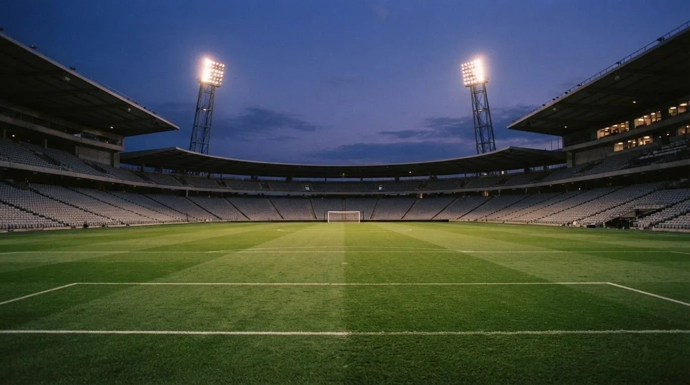 Een leeg voetbalstadion met lichtmasten bij schemering