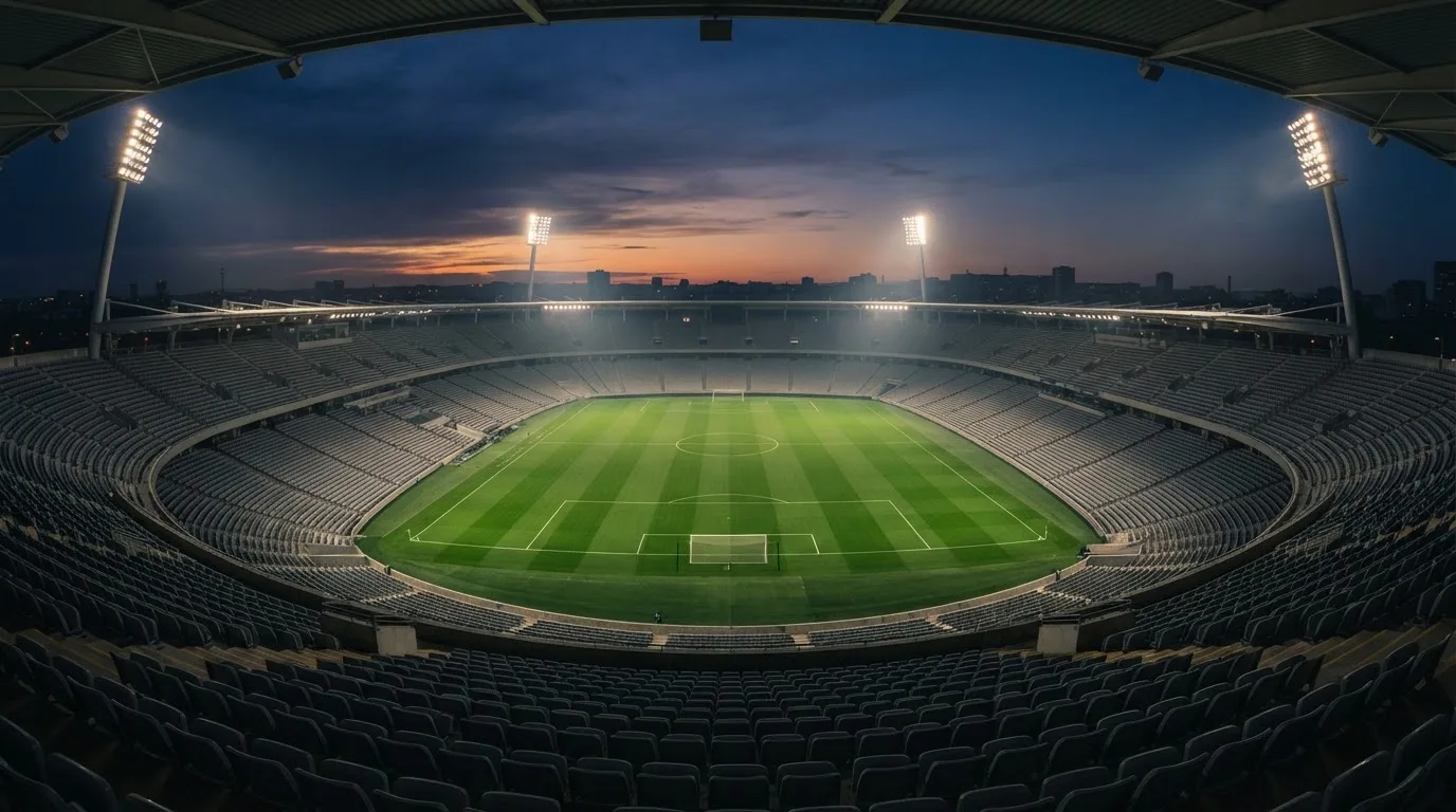 Een leeg voetbalstadion met lichtmasten bij schemering