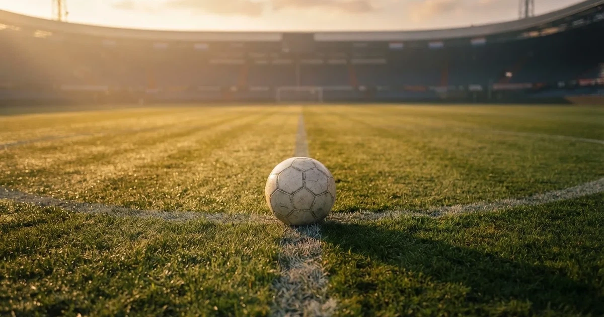 Een voetbal op de middenstip van een grasveld in het ochtendlicht