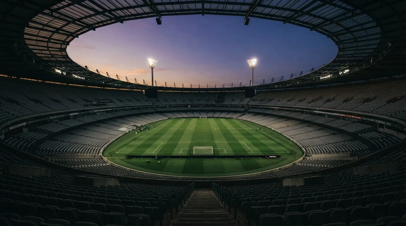 Een leeg voetbalstadion met lichtmasten bij schemering