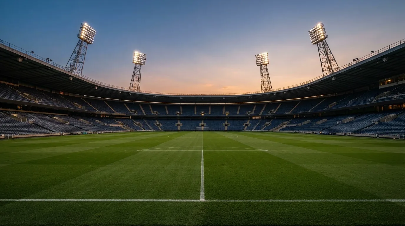 Een leeg voetbalstadion met lichtmasten bij schemering