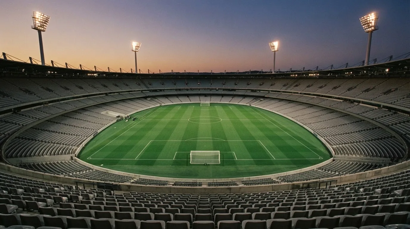 Een leeg voetbalstadion met lichtmasten bij schemering