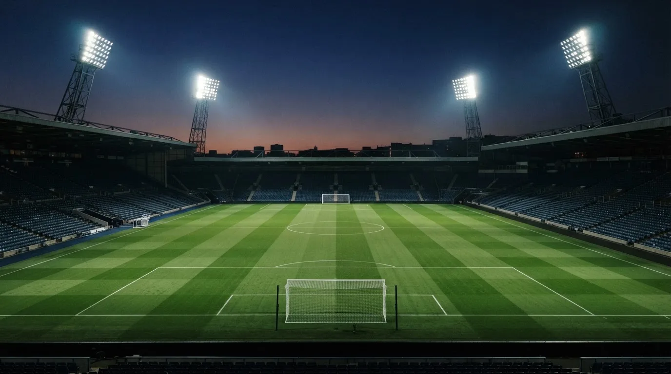 Een leeg voetbalstadion met lichtmasten bij schemering