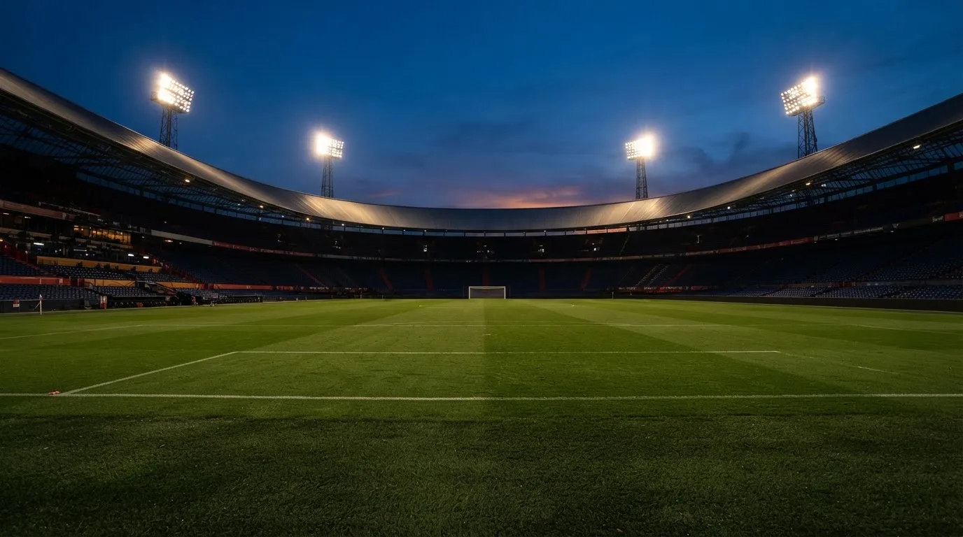 Een leeg voetbalstadion met lichtmasten bij schemering