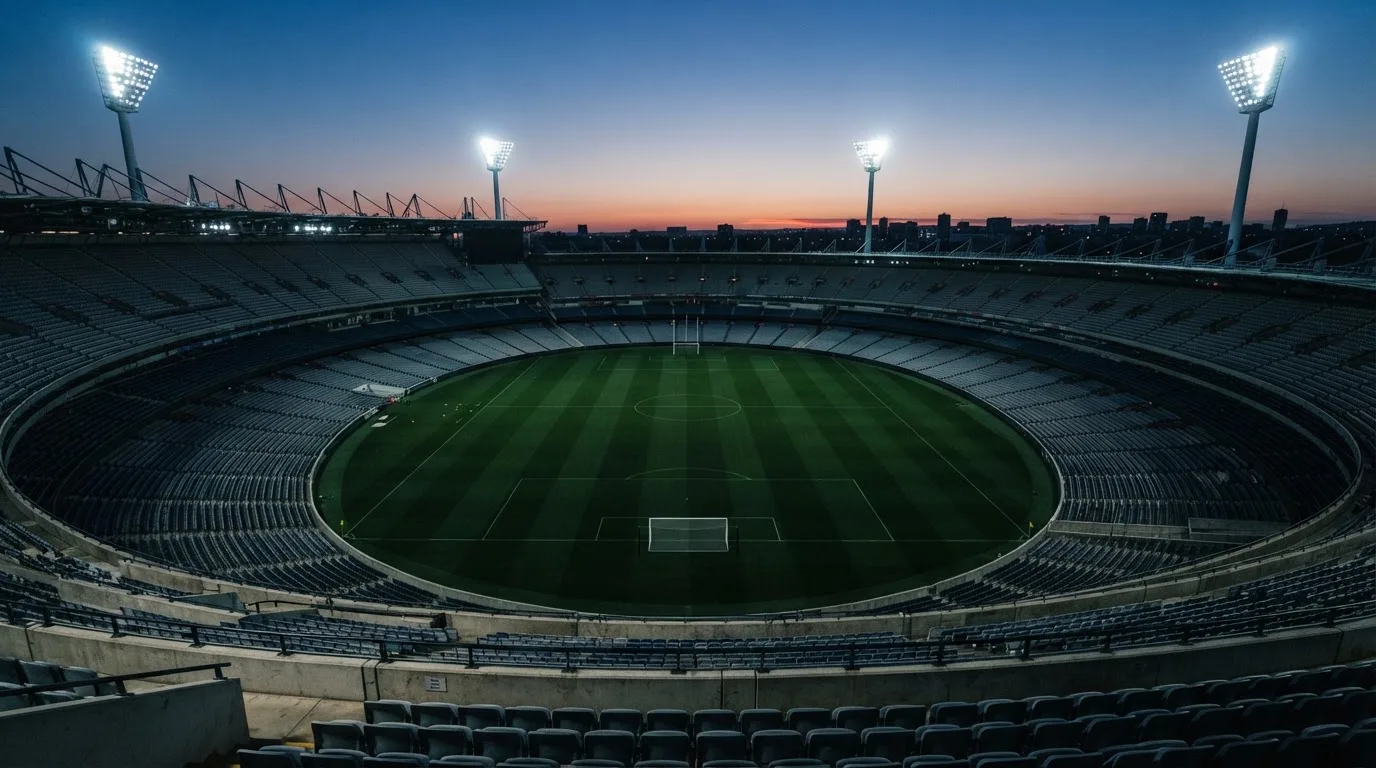 Een leeg voetbalstadion met lichtmasten bij schemering