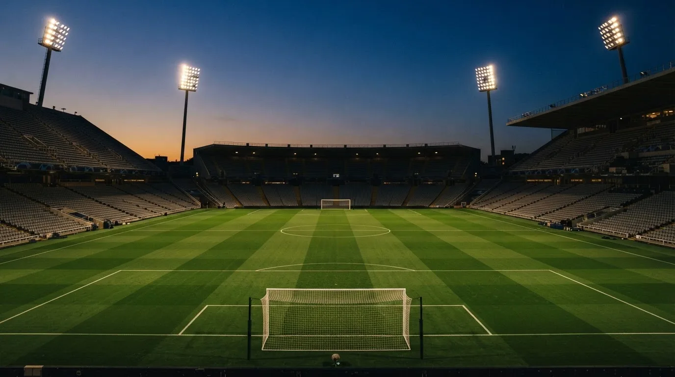 Een leeg voetbalstadion met lichtmasten bij schemering