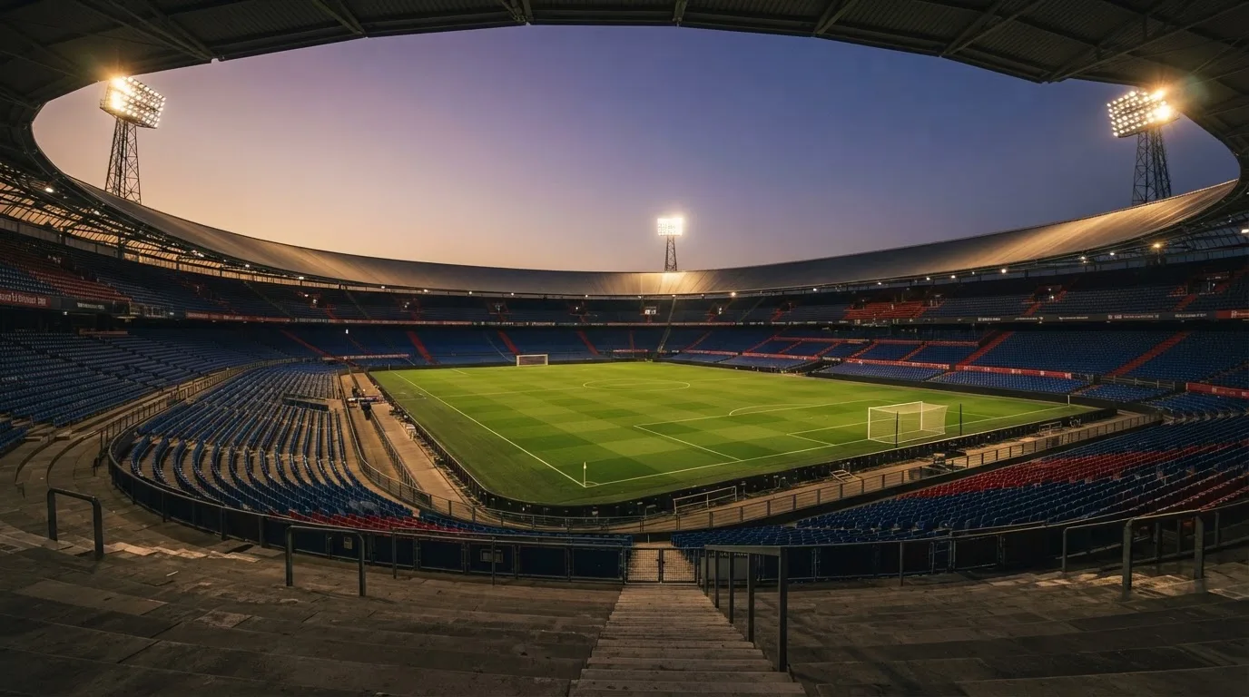 Een leeg voetbalstadion met lichtmasten bij schemering