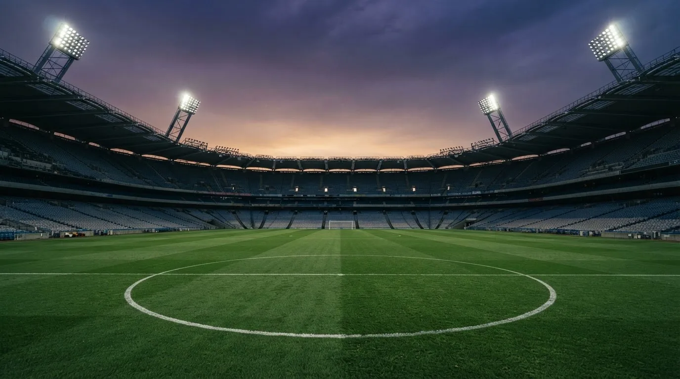 Een leeg voetbalstadion met lichtmasten bij schemering