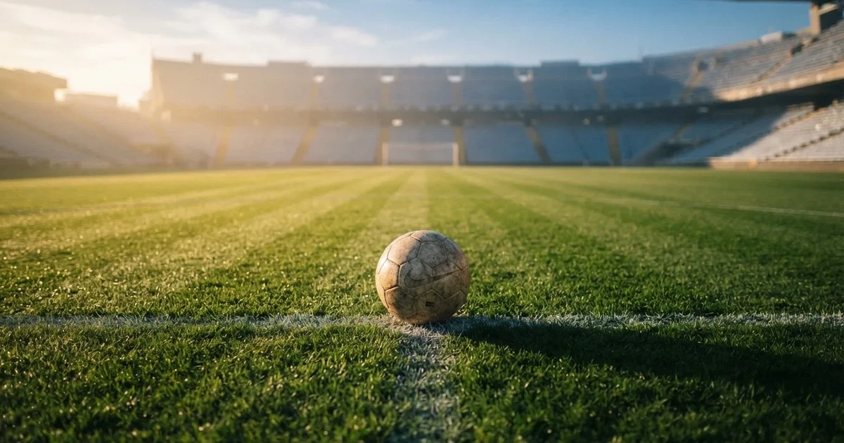 Een voetbal op de middenstip van een grasveld in het ochtendlicht