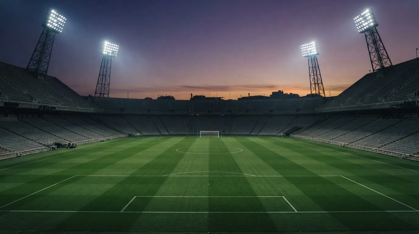 Een leeg voetbalstadion met lichtmasten bij schemering