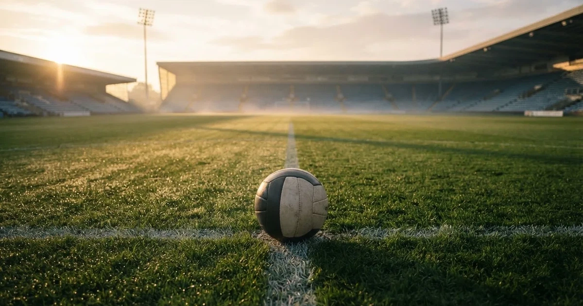 Een voetbal op de middenstip van een grasveld in het ochtendlicht