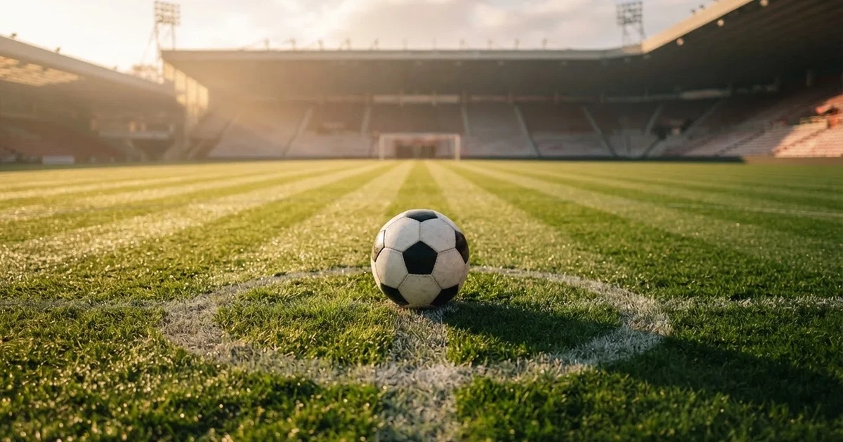 Een voetbal op de middenstip van een grasveld in het ochtendlicht